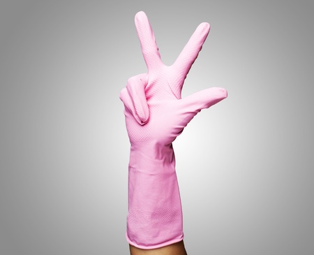 pink gloves of maid gesturing number three against a grey backgroundの写真素材