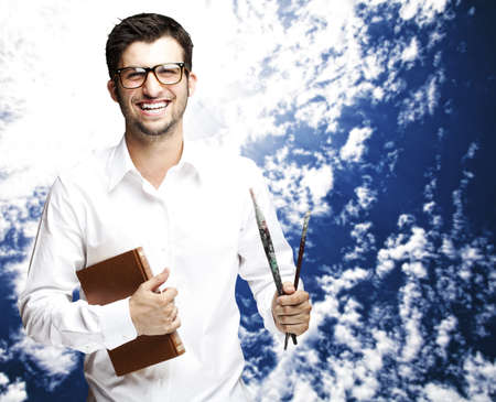 portrait of young student ready to paint against a cloudy sky background