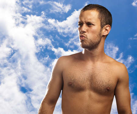 young man smiling against a blue sky backgroundの写真素材