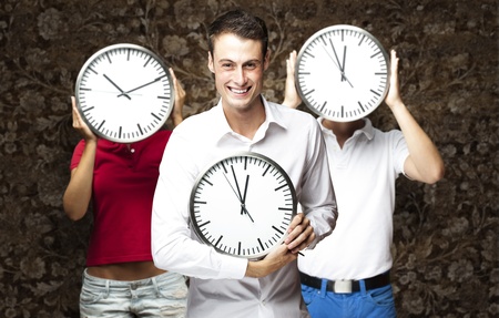 group of young students holding clock against a vintage wallの写真素材