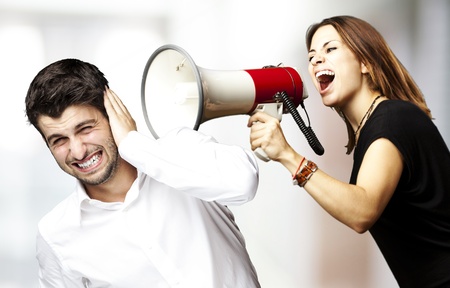young woman screaming a man with the megaphone against a abstract backgroundの写真素材