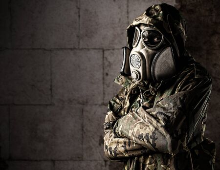 portrait of soldier with gas mask leaning against the wallの写真素材