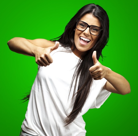 portrait of a pretty woman doing approve symbol over green backgroundの写真素材