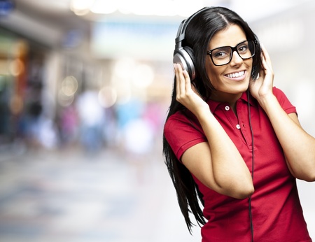 portrait of young woman listening to music against a crowded placeの写真素材