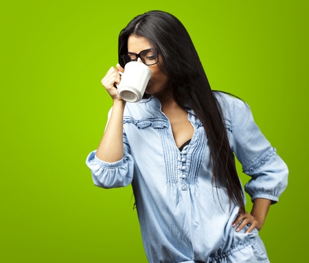portrait of a pretty young woman drinking coffee on a cup against a green backgroundの写真素材