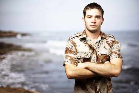 portrait of a serious young soldier standing against a sea backgroundの写真素材