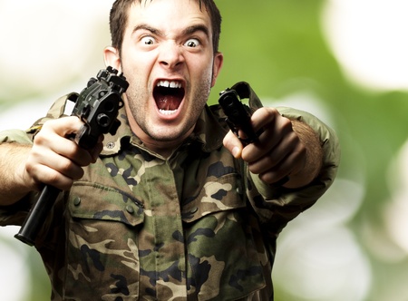 portrait of a young soldier aiming with pistol against a abstract backgroundの写真素材