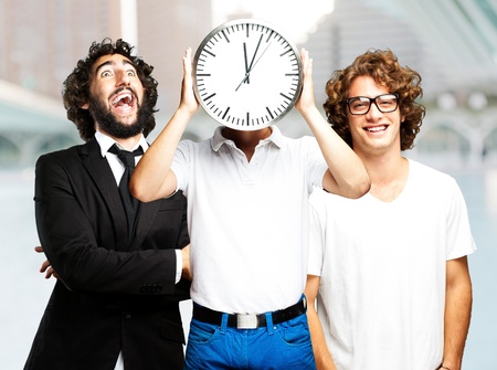 young man holding clock with friends at cityの写真素材
