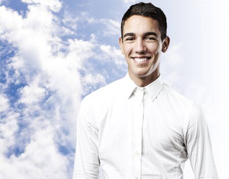 portrait of handsome young man smiling against a blue sky backgroundの写真素材