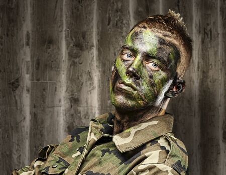 portrait of young soldier with jungle camouflage paint against a grunge backgroundの写真素材
