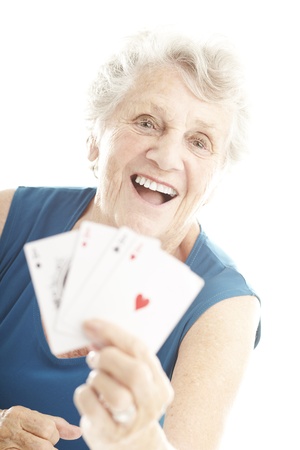 portrait of senior woman showing poker cards over whiteの写真素材