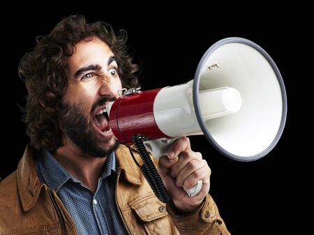 portrait of young man shouting with megaphone against a black backgroundの写真素材