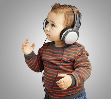 young boy wearing headphones and listening to music against a grey backgroundの写真素材