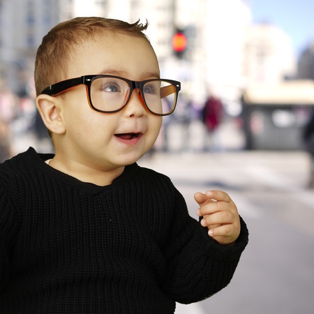young boy wearing glasses and laughing against a street backgroundの写真素材