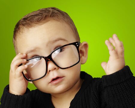 young boy wearing glasses and looking up against a green backgroundの写真素材