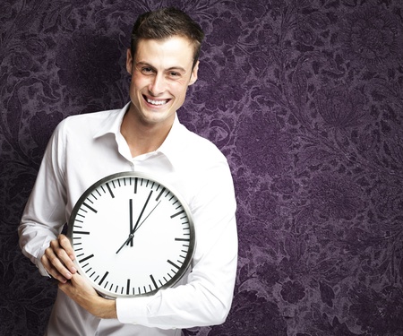 portrait of young man holding clock against a vintage backgroundの写真素材