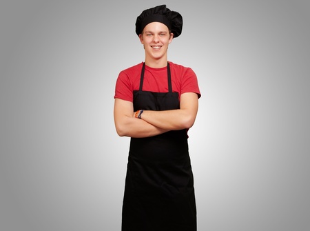 portrait of young cook man wearing uniform and smiling over grey backgroundの写真素材