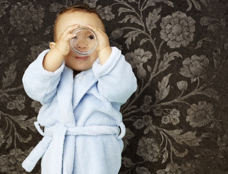 boy with bathrobe drinking water against a vintage background