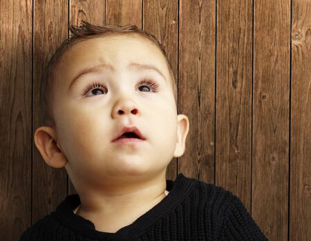 young boy looking up against a wooden background