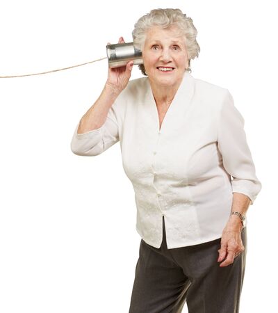 portrait of senior woman hearing with metal tin can over white backgroundの写真素材