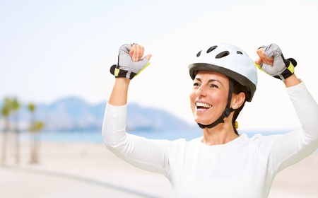 portrait of a cheerful sporty middle aged woman doing a victory symbol near the beachの写真素材