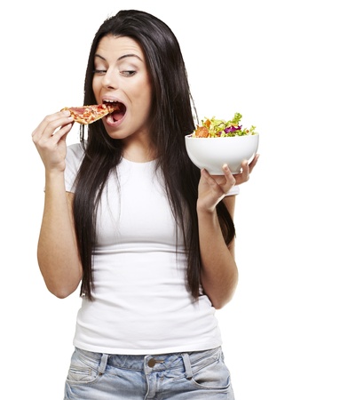 woman choosing a slice of pizza instead of a salad against a white backgroundの写真素材