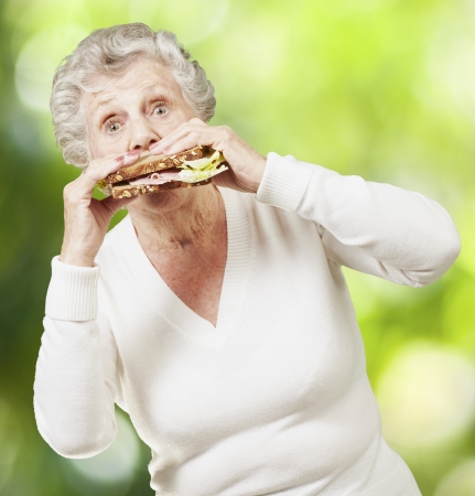 senior woman eating a healthy sandwich against a nature backgroundの写真素材