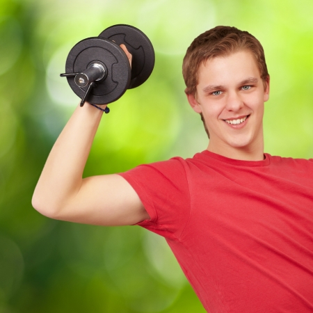 young man doing fitness with weights against a nature backgroundの写真素材
