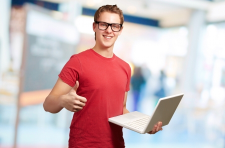 Man holding laptop with thumbs up, indoorの写真素材
