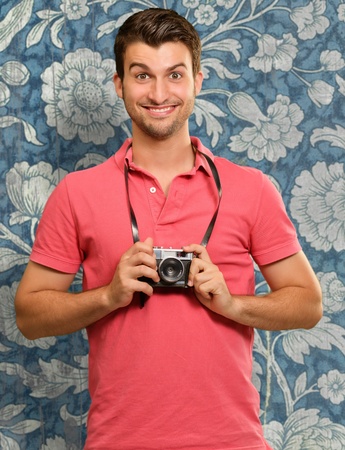 Portrait of a man holding camera on wallpaperの写真素材