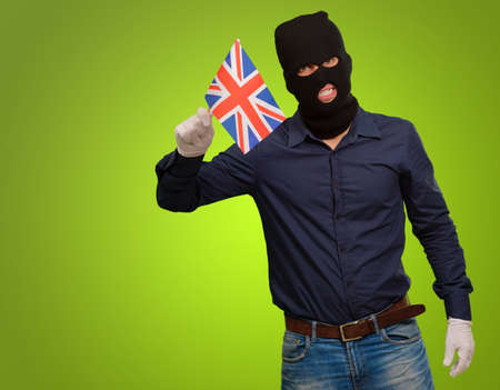 Portrait of a man wearing mask holding a flag isolated on green background