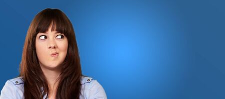 A Young Girl Holding A Clock And Making Face On Blue Background