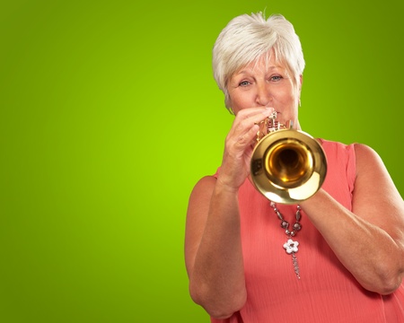 Mature Woman Blowing Her Trumpet Isolated On Green Background