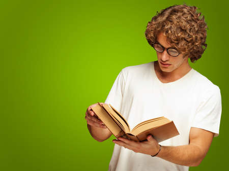 Portrait Of A Man Reading A Book Isolated On Green Backgroundの写真素材