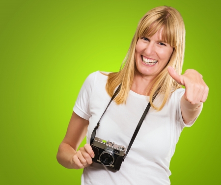 Happy Woman With Old Camera Showing Thumb Up against a green backgroundの写真素材