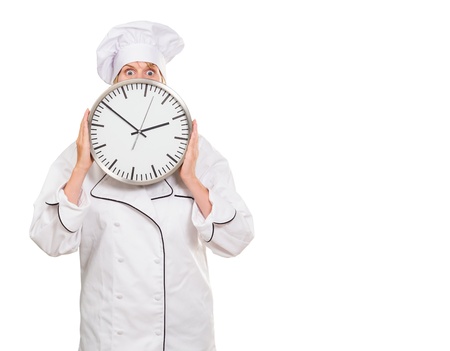 worried chef hiding behind a clock against a white backgroundの写真素材