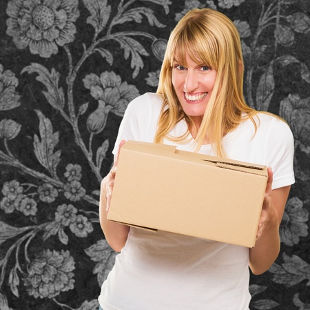 Woman Holding Cardboard box against a floral pattern backgroundの写真素材