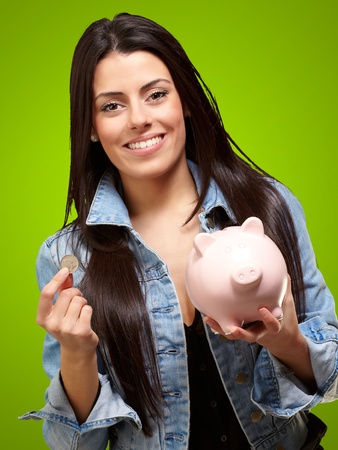 Portrait Of A Female Holding A Coin And Piggybank On A Green Backgroundの写真素材