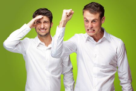 Portrait Of Angry Man With Frustrated Man Behind On Green Backgroundの写真素材