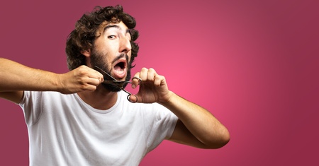 Man Cutting Beard against a pink backgroundの写真素材