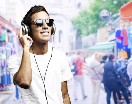 portrait of a young boy listening to music against a street backgroundの写真素材