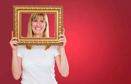 Woman Holding Up A Picture Frame against a red background