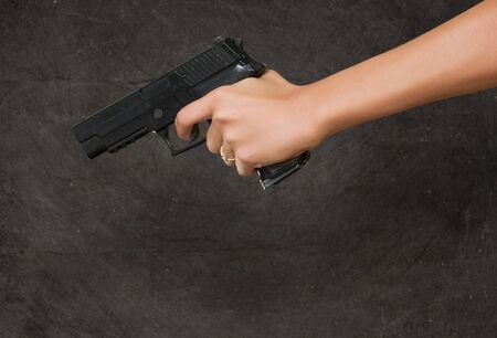 Woman's Hand With A Gun against a grunge backgroundの写真素材