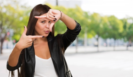 Young Woman Making Frame With Fingers against a street backgroundの写真素材
