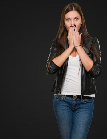 Surprised Woman covering her mouth against a black backgroundの写真素材
