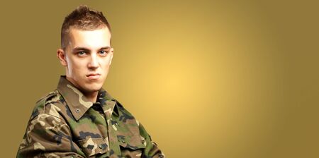 Portrait Of Angry Soldier against a yellow backgroundの写真素材