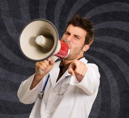 Doctor Shouting In Megaphone And Gesturing Against Wallpaperの写真素材
