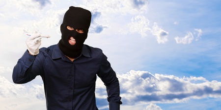 Man wearing robber mask and holding airplane miniature, outdoorの写真素材
