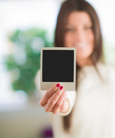 Woman Holding Blank Instant Photo, Indoors
の写真素材