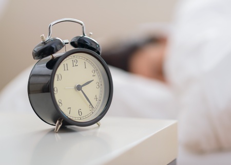 Alarm Clock In Front Of A Person Sleeping